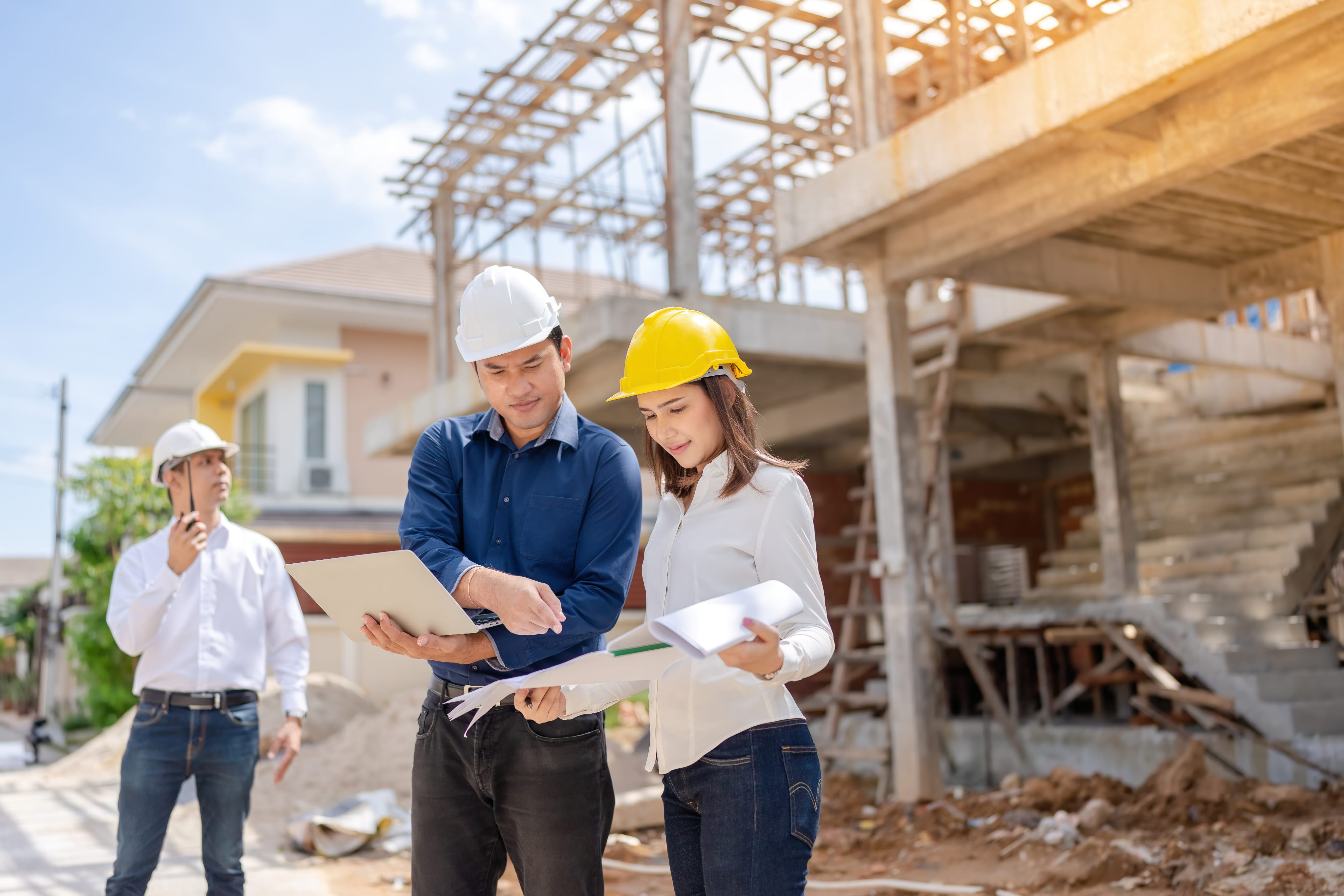 Kỹ sư xây dựng kiểm tra dự án với máy tính xách tay và bản vẽ - Quỹ Tín Dụng Nhân Dân Duy Thanh hỗ trợ vay vốn bất động sản